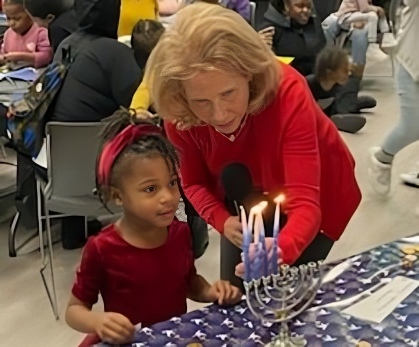 Shari Redstone lighting a Menorah with a child at the YMCA