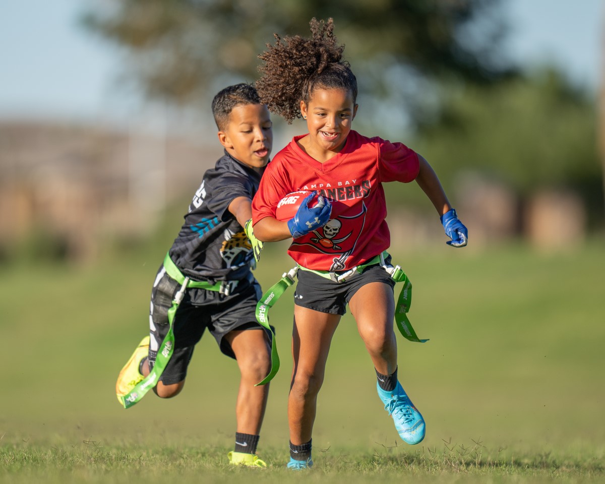 Two children playing nfl flag football.